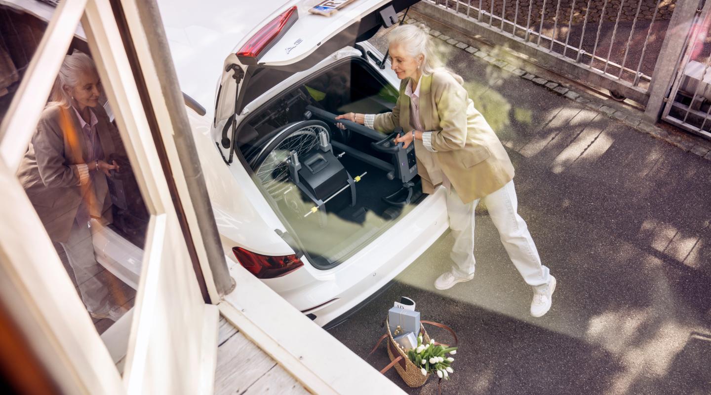 Frau lädt mobilen Treppensteiger scalamobil in Kofferraum ihres Kleinwagens