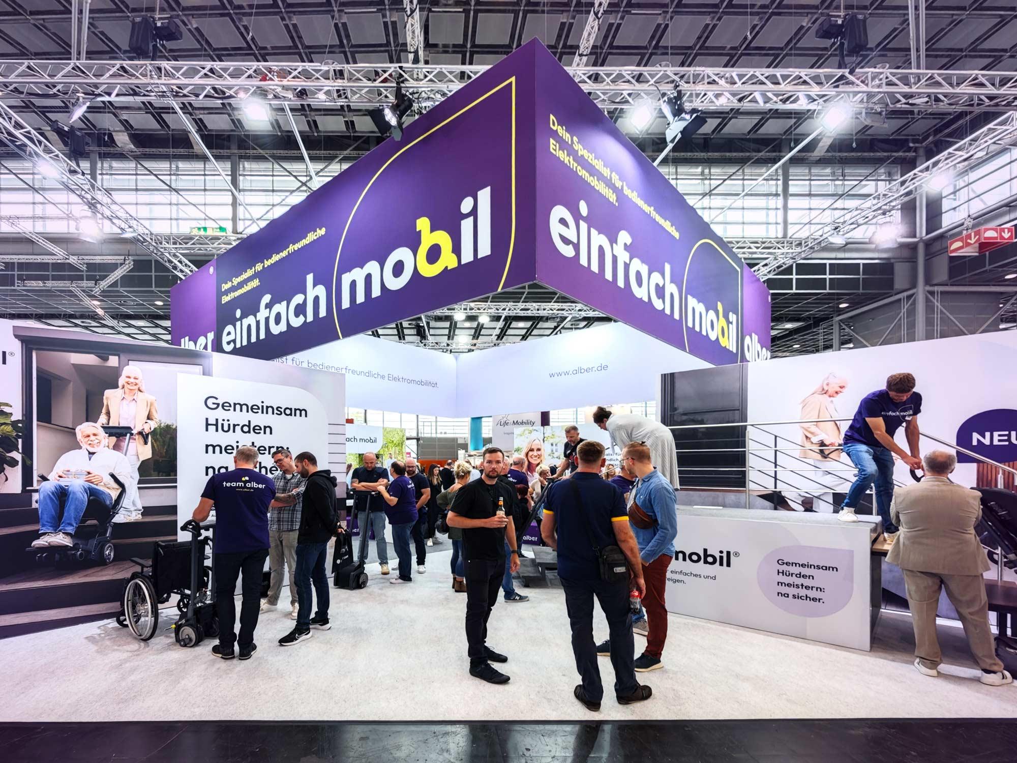 Messestand von Alber auf der Rehacare 2024 unter dem Motto einfach mobil auf großem lila Banner