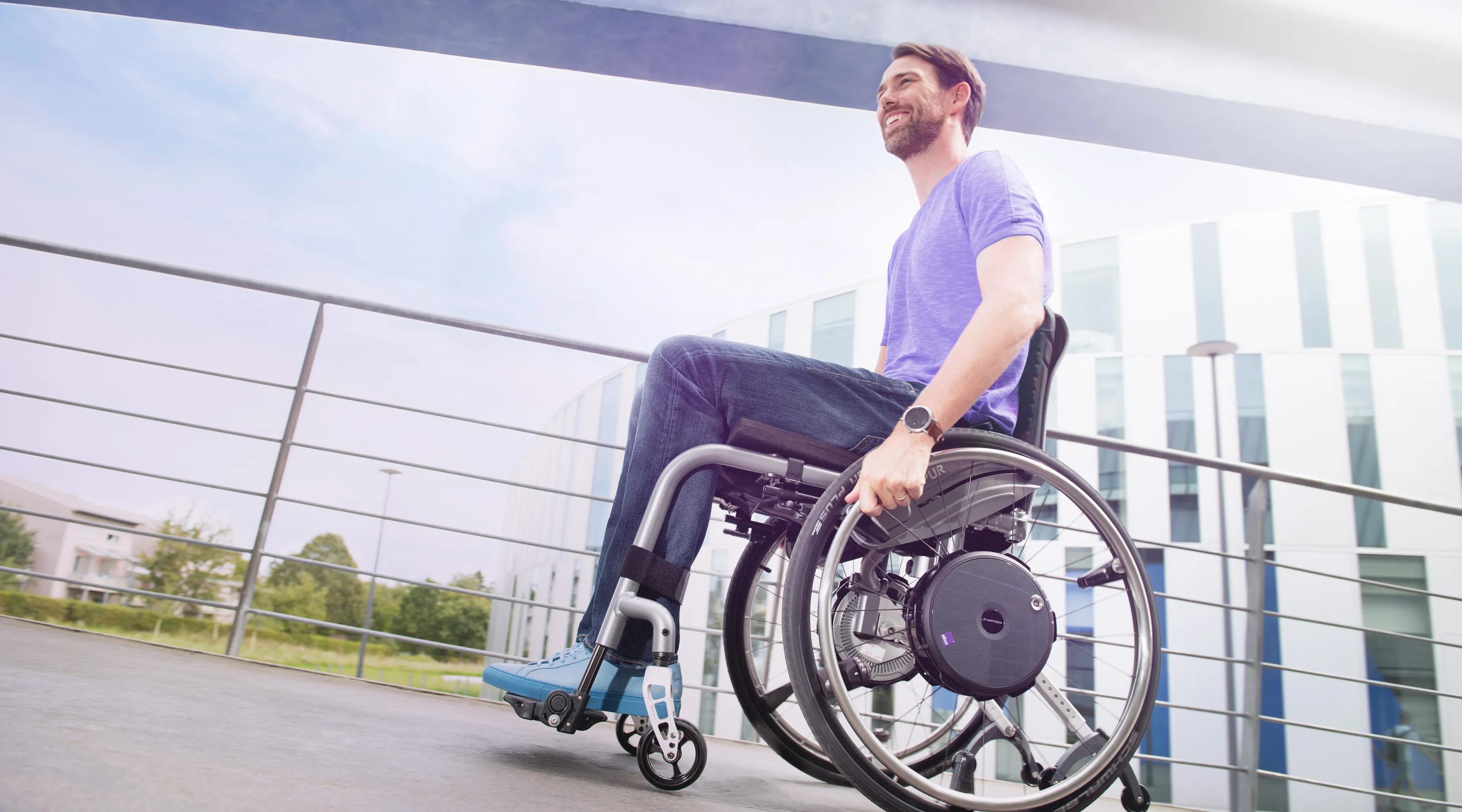 Mann fährt mit Rollstuhl Zusatzantrieb e-motion von Alber eine Rampe hinauf