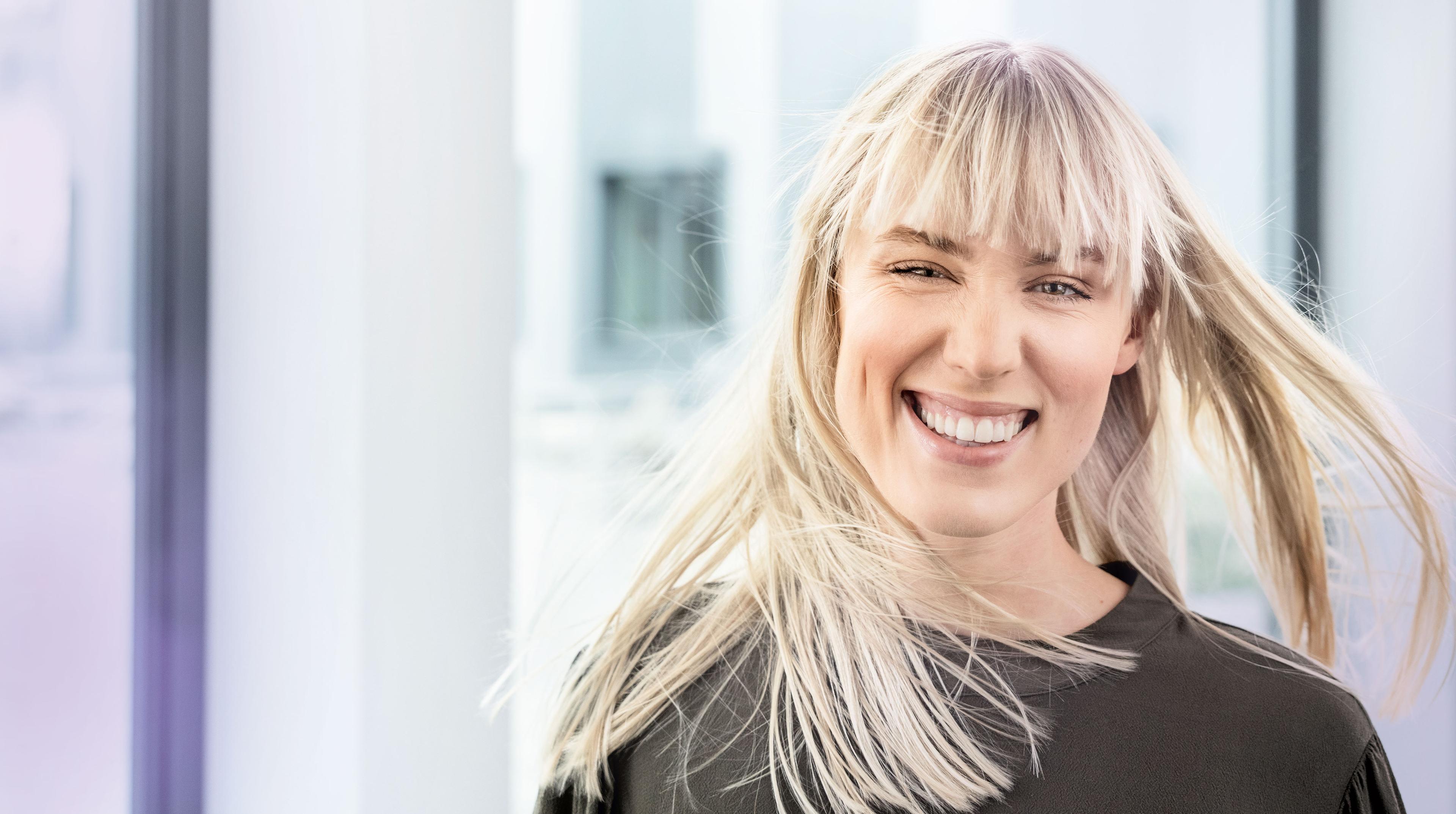 Lächelnde junge Frau mit optimistischem Gesichtsausdruck.