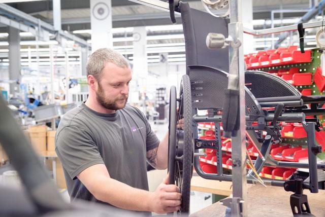Ein Mitarbeiter der Alber GmbH prüft ein Rollstuhl-Rad in der Alber Produktionshalle in Albstadt