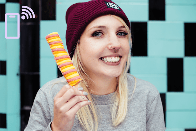 Porträt einer jungen Frau mit rot-orangem Twister-Eis in einer Hand.