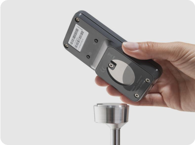 Hand hält Magnethalterung für ECS-Fernbedienung – Blick auf Rückseite Magnet und Halterung