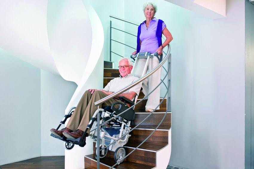 Eine Frau befördert ihren Mann mit dem Scalamobil die Treppe hinunter.
