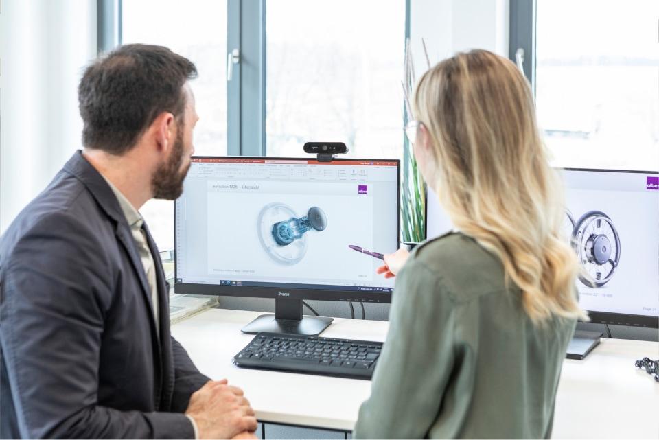Eine Frau und ein Mann aus dem Alber Experten Team sprechen über e-motion  Antriebsskizze auf Computerbildschirm