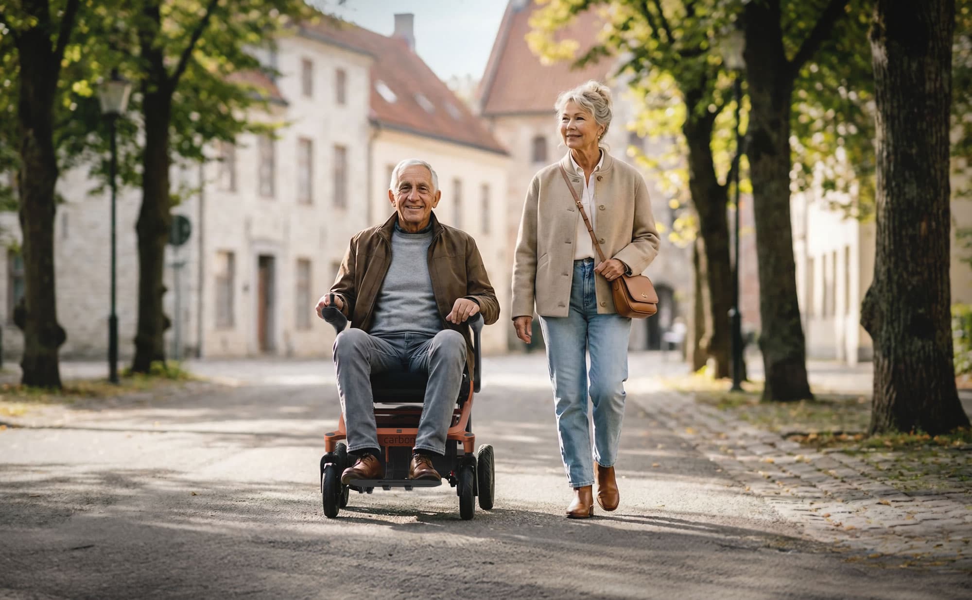 Frau mit Mann in faltbarem E-Rollstuhl erivo carbon machen einen Spaziergang durch einen sonnigen Park.