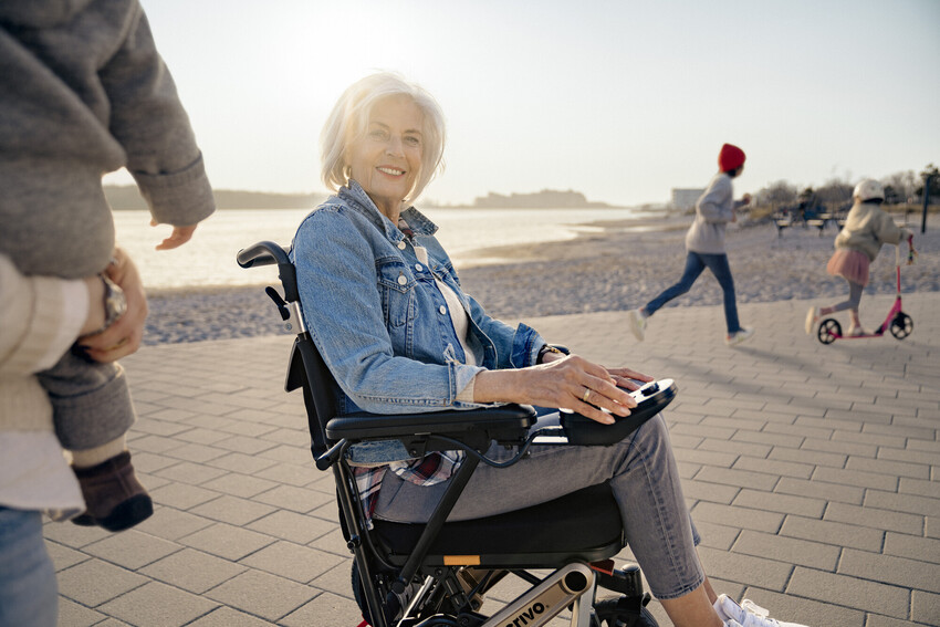 Frau steuert elektrischen Rollstuhl mit Joystick